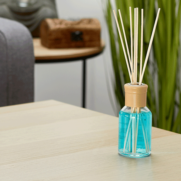 Raumduft-Flakon mit Holzstäbchen auf Holztisch – stilvolle Raumduft-Deko. Großhandel für Deko- & Geschenkartikel